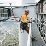 Worker secured with safety harness doing inspection on high metal platform